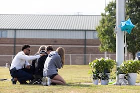 State of Georgia Chaplain Ronald Clark consoles students as they kneel in front of a makeshift memorial at Apalachee High School on Thursday in Winder, Ga.